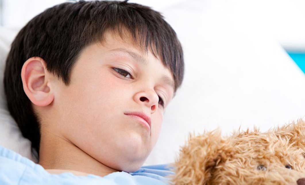 Kleiner Junge liegt im Bett mit einem Teddy. N